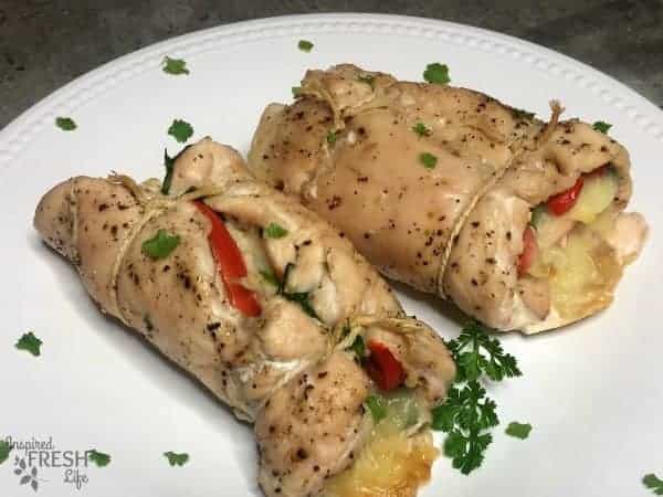 Spinach Stuffed Rolled Chicken on a white plate with parsley garnish.