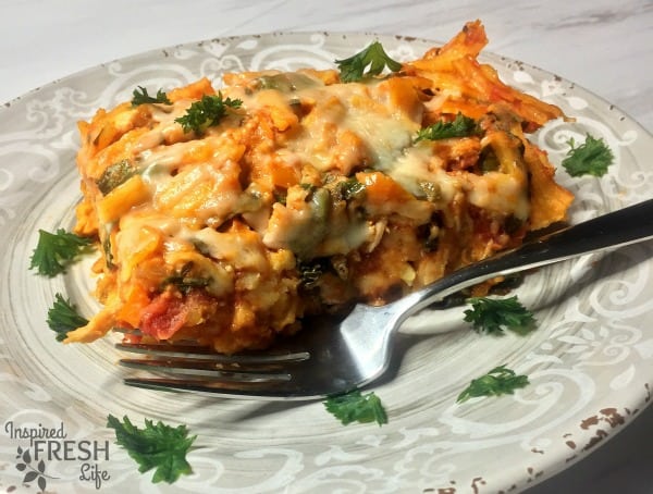 A slice of butternut squash pasta bake on a plate with a fork