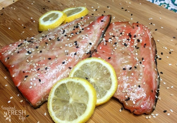 Miso Ginger Cedar Plank Salmon garnished with lemon wheels and sesame seeds.