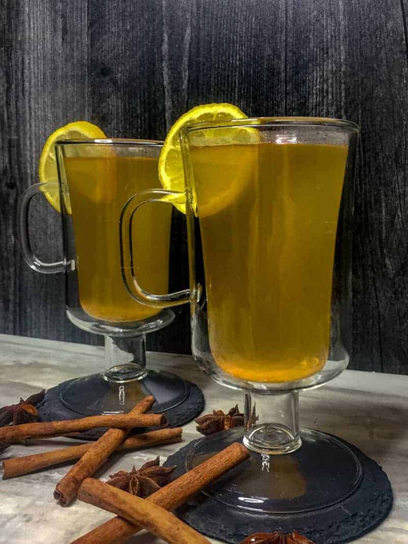 Spiced Hot Toddy with a lemon wheel garnish and cinnamon sticks and star anise at the base.