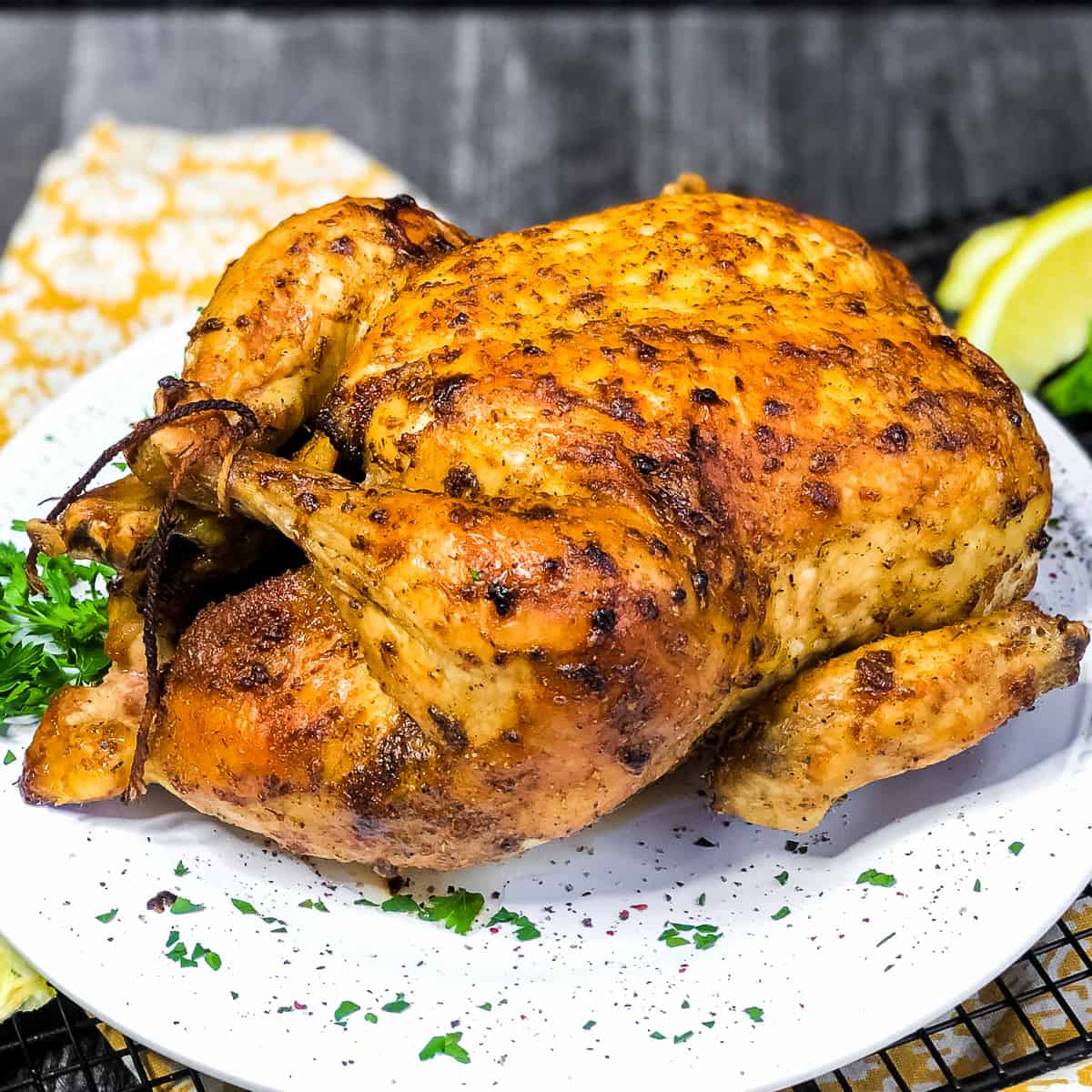 Air Fryer Whole Chicken on a white plate garnished with parsley.