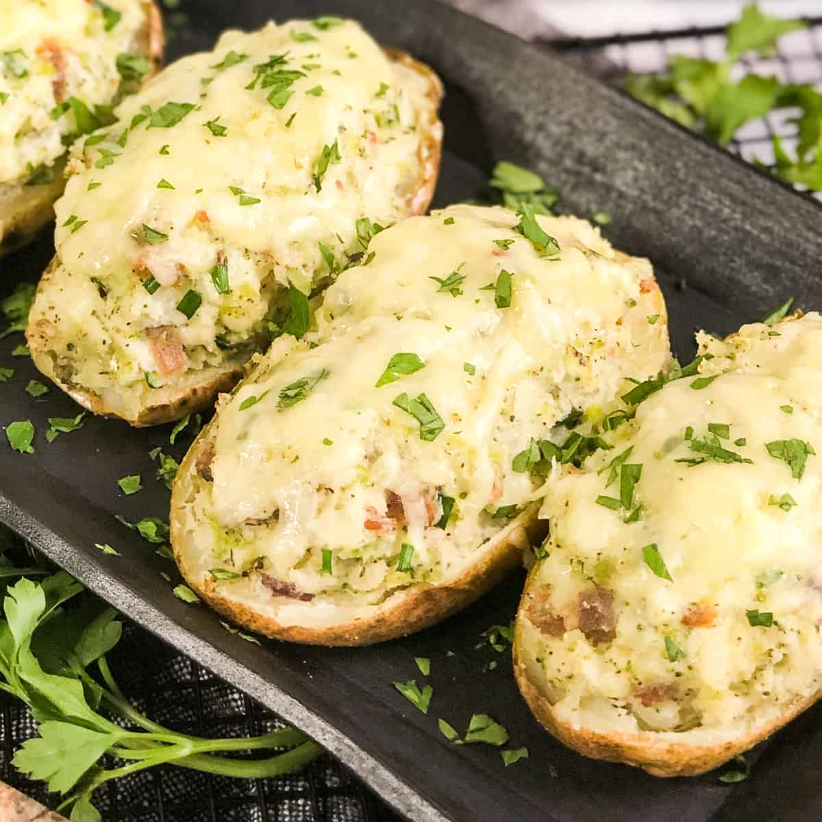 Air Fryer Twice Baked Potatoes on a black platter garnished with parsley.