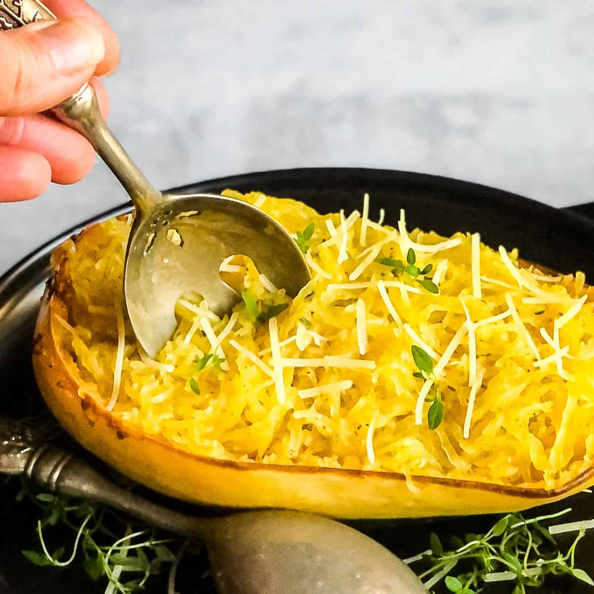 Hand with a spoon digging into Roasted Spaghetti Squash.