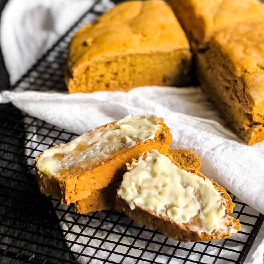 Close up of sliced Irish Soda Bread slathered with butter with remaining loaf blurred in background.