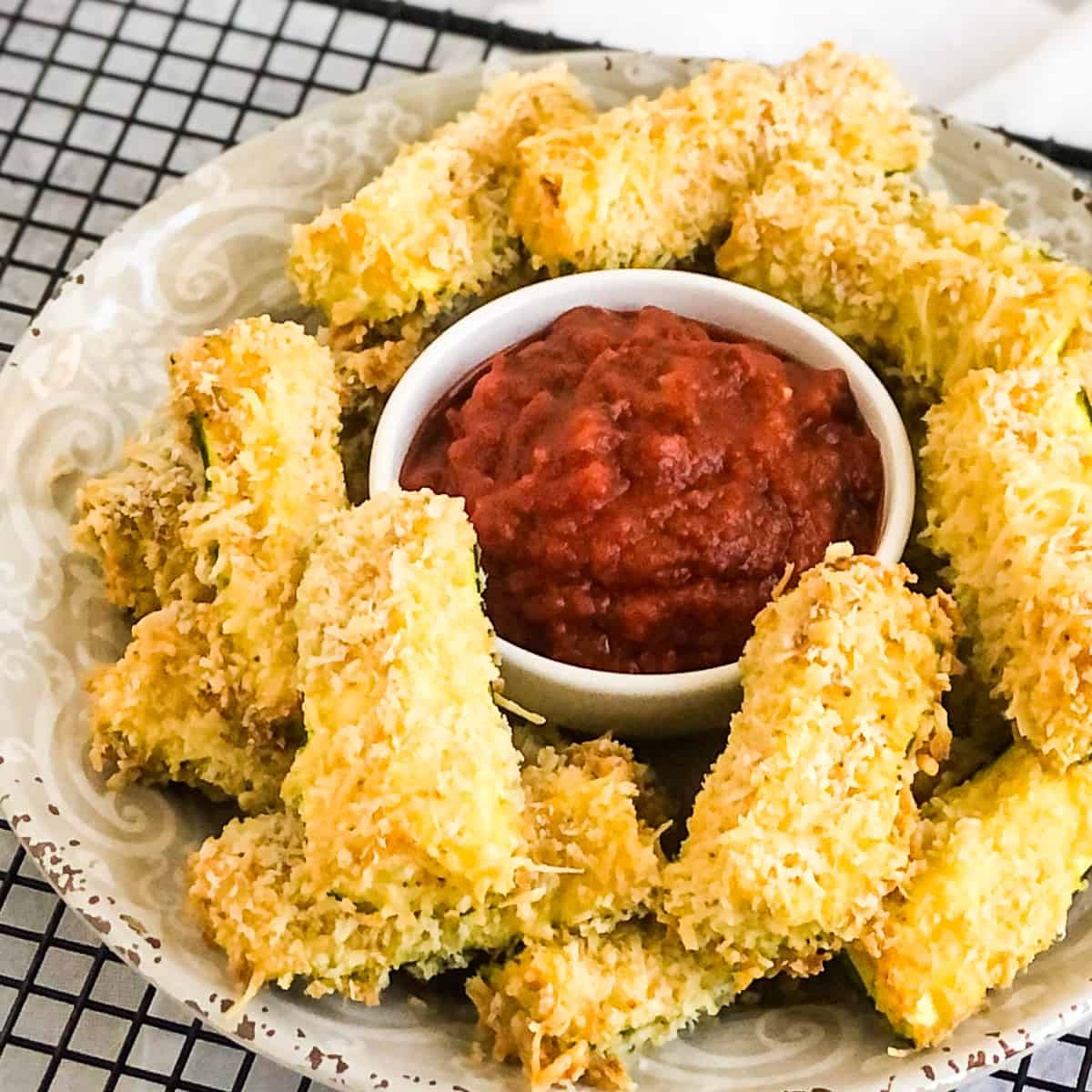Air Fryer Zucchini Fries on a white plate with marinara dipping sauce in center.