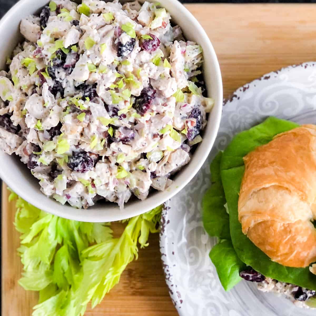 Bowl of chicken salad next to a croissant sandwich.