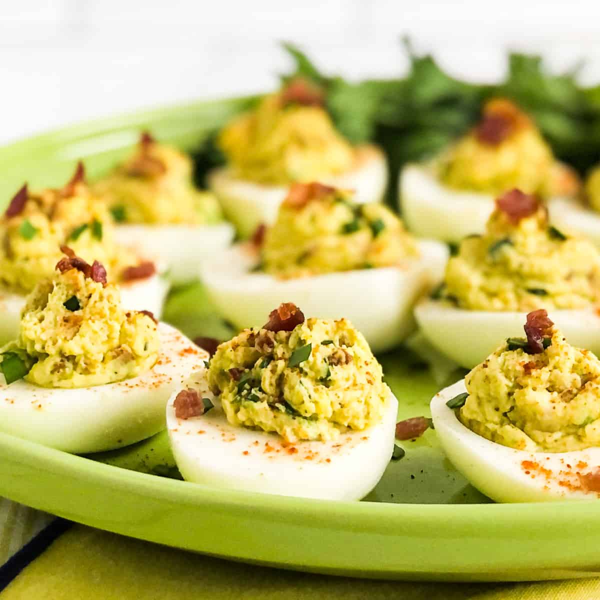 Avocado Deviled Eggs on a green plate garnished with parsley in the background.