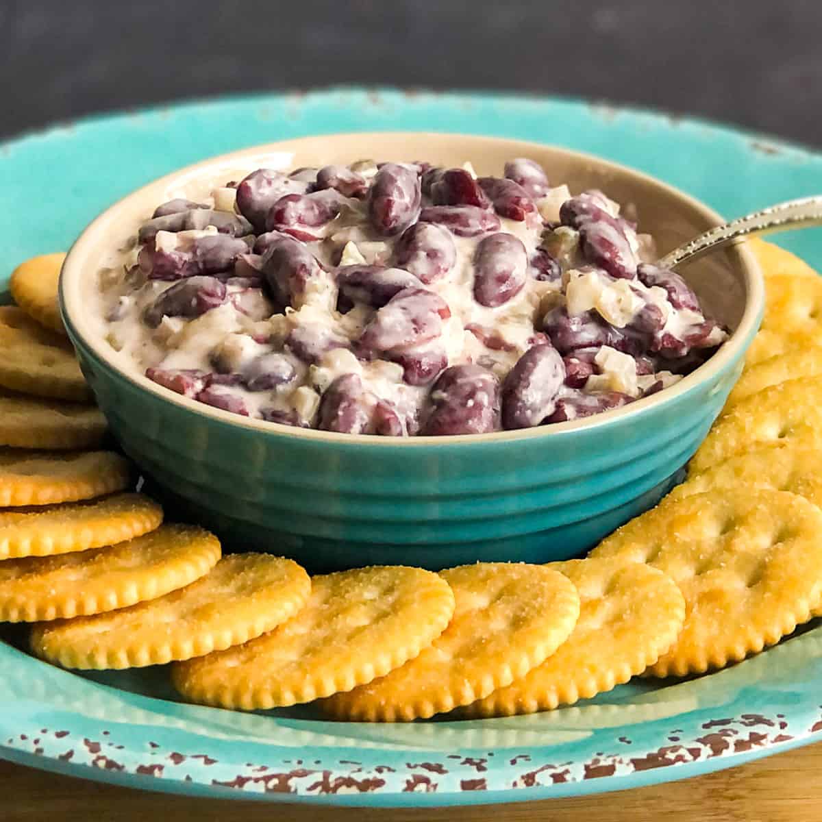 New England Bean Dip in a blue bowl with crackers in foreground.