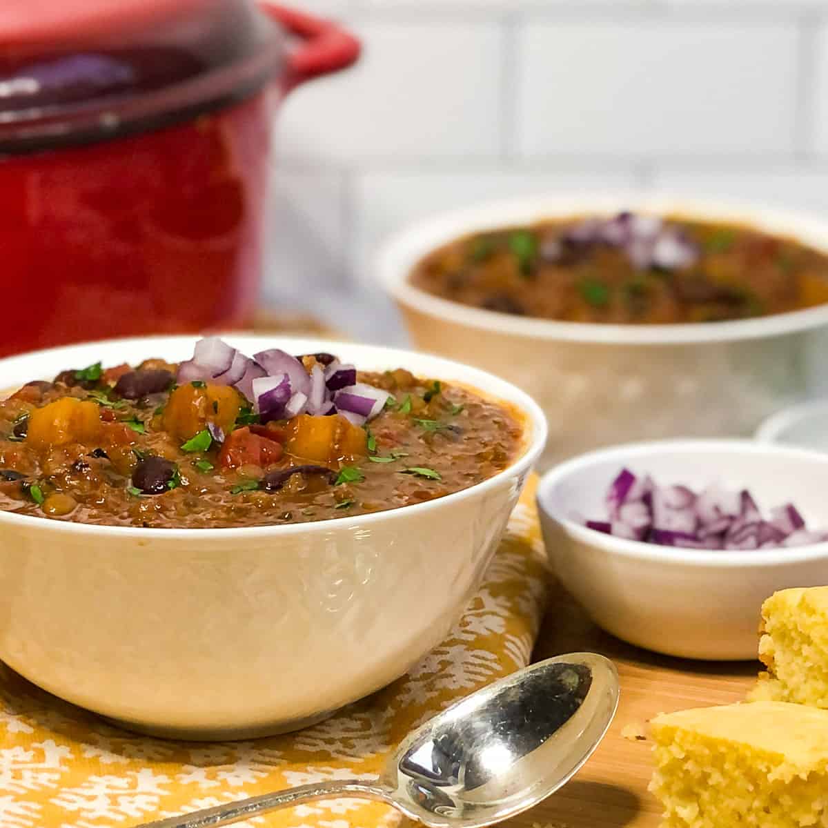 Two bowls of vegetarian chili in front of a Dutch oven.